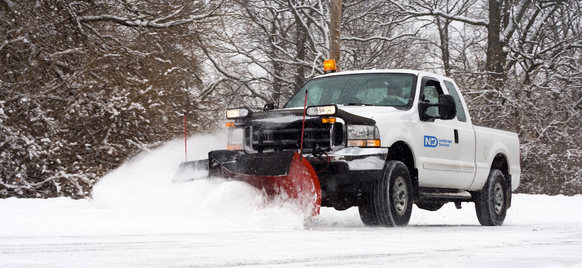 Company vehicle snowplowing a walkway.